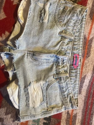 Ljusa denimshorts från Edikted - Säljer ett par ljusblå denimshorts från Edikted med råa kanter och slitna detaljer framtill. Shortsen har låg midja och korta ben. Perfekt för sommar och utlandssemester. Finns ett litet hål på insidan på varje sida av dragkedjan pga de var för stora för mig så jag fick lösa det med ett snöre, men det är inget som syns på utsidan! Använda ett fåtal ggr. Org pris 719:-. Ditt pris 400:- skicka dm vid frågor.