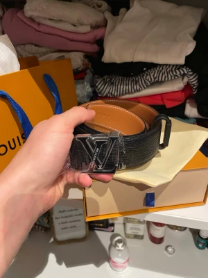NY! Louis Vuitton LV Initiales – Reversibelt läderbälte 40 mm - Säljer ett helt nytt och oanvänt Louis Vuitton LV Initiales-bälte. Modellen är reversibel med svart läder på ena sidan och ljusbrunt på den andra. Det klassiska LV-spännet i metall ger ett tidlöst och elegant uttryck. Bältet är i nyskick och levereras med originalkartong och dustbag. Nypris i butik ligger runt 7 000–7 500 kr. Kan skickas eller mötas upp enligt överenskommelse.
