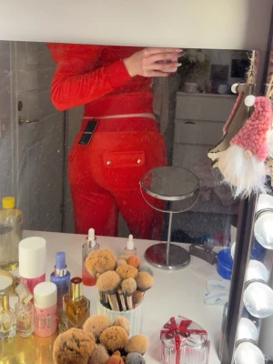 Juicy Couture rött set - Säljer ett par röda mjukisbyxor från Juicy Couture med snörning i midjan och fickor med lock och knappar bak. Byxorna är i mjuk sammet och har en lågmidjad passform som ger en chill vibe. Perfekt för dig som vill ha en comfy och snygg look. Köptes för en månad sen och retur dagar är 14 dagar så får sälja. Byxor i M tröja i S. Nypris 2250kr. Prislappar finns kvar.