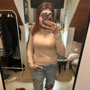 Rosa beige tight långärmad tröja med guld knappar från zara  - Säljer en puderosa beige tight stickad långärmad tröja med snygga knappdetaljer vid ärmsluten. Tröjan har en slim passform och är enkel men stilren, perfekt att matcha med jeans eller kjol. Materialet känns mjukt och skönt mot huden. 