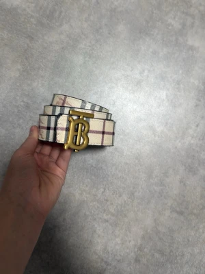 Rutig beige skärp från Burberry - Den är lite använd som man ser i bilden det är inte synligt när du har på dig den men när du böjer på den så kommer den att visas lite!