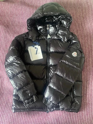 Moncler Maya - En Moncler Maya helt utan defekter. I mina ögon den snyggaste jackan på marknaden - passar till allt och är otroligt stilren. Storlek 2 vilket motsvarar M.  OBS: Kan ej 100% garantera att den är äkta då jag ärvt den från min storebror som jag inte har kontakt med längre. Man kan såklart göra en egen legitcheck men så långt som jag har kollat ser den väldigt bra ut. Kontakta mig om frågor!😊