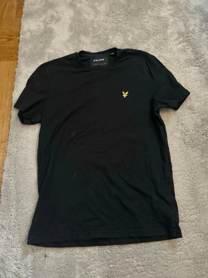 Svart t-shirt från Lyle & Scott - Svart t-shirt från Lyle & Scott. Storlek S. Den har någon fläck därframme (ser på bilden ) annars e den i fint skick. Fläcken kanske går bort i tvätten. 