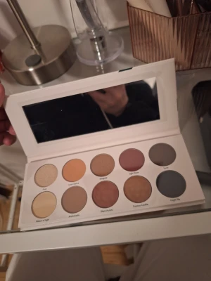 Ögonskuggspalett med 10 neutrala toner - Snygg ögonskuggspalett med tio olika nyanser i neutrala och skimmriga färger, från beige och brunt till grått och guld. Paletten har en spegel i locket. Perfekt för både vardagar men också fest.