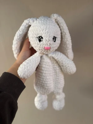 Vit virkad kanin snuttefilt - Supermjuk och fluffig snuttefilt i form av en vit kanin med långa öron och broderade ögon. Tillverkad i virkat garn med rosa nos och söta detaljer. Perfekt som gosedjur eller trygghet för barn.