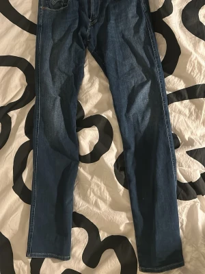 Replay anbass jeans - Ett par riktigt sköna blå replay anbass hyperflex jeans i slim fit med storleken 34 (34/34). Jeansen har fem fickor och har ett väldigt bekvämt material. Säljer då de är för små för mig. Jeansen har lite tecken på användning men inget man märker. Nypris ca 1750kr. Kontakta mig gärna om du har frågor!