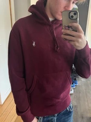 Vinröd hoodie från Ralph Lauren - Kolla in mina andra plagg!!! Snygg vinröd hoodie från Ralph Lauren med klassisk logga broderad på bröstet. Hoodien har huva med dragsko och en stor magficka. Perfekt till jeans för en chill look.