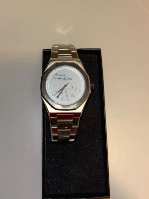 Rolex ”Who cares I’m already late” liknande  -  Silvrig Rolex liknande klocka med texten 'Who cares, I'm already late' på urtavlan och ett metallarmband. Helt ny.