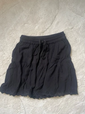 Svart kortkjol med snörning - Svart kortkjol med resår och snörning i midjan. Kjolen är aldrig använd!💗