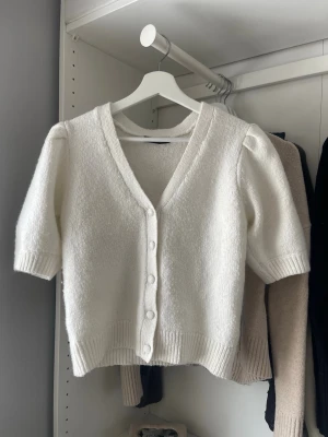 Vit kortärmad kofta med puffärm - Söt vit kofta med korta puffärmar och v-ringning. Använd fåtal gånger och passar perfekt till vardagen!💗