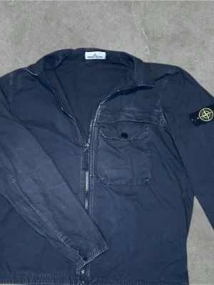 ÄKTA Stone Island Over-Shirt - Riktigt fet Stone Island Overshirt-Shirt🪨🏝️  Storlek Xl ‼️Sitter som M-L‼️ Mått📏 Axelbredd: 50cm (ca) längd: 70cm (ca) Svart,grå🩶🖤 ✅‼️SJÄLVKLART ÄKTA‼️✅ Mycket bra skick😊🙏 Skickas med PostNord inom 24h efter köp📦➡️ Kom med bud😊🤩 För mer frågor och information svarar jag snabbt📞💨