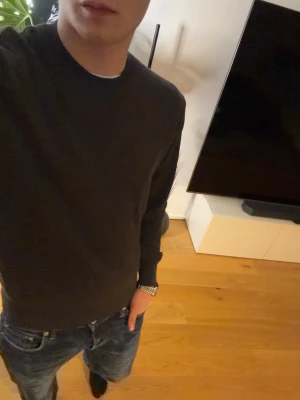 Mörkgrå stickad tröja Sandö - Mörkgrå stickad tröja från Sandö i klassisk modell med rund halsringning och ribbade muddar. Perfekt basplagg som funkar till det mesta. Materialet känns mjukt och bekvämt, och färgen är lätt att matcha med jeans eller andra byxor. Passar mig som är 177, 