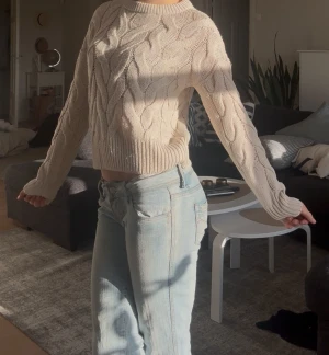 Beige stickad kabeltröja - Säljer en beige stickad tröja med snyggt kabelmönster och ribbade muddar vid ärmslut och nederkant. Ifrån Kapphal. Mycket fin säljes för 200kr