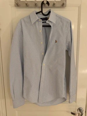 Blårandig skjorta Polo Ralph Lauren XS - En stilig blårandig skjorta från Polo Ralph Lauren i slim fit-modell. Klassisk krage, långa ärmar och knappar framtill. Broderad logga på bröstet. Skjortan är gjord i mjuk bomull och helt oandvänd. Pris går att diskutera.