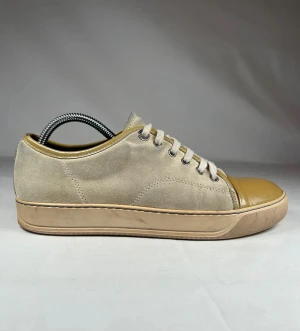 Lanvin Beige sneakers med mocka och lackad tå - Snygga beige sneakers med ovandel i mjuk mocka och glansig, lackad tå i ljusbrun ton. Skorna har rund tå, platt sula och snörning med metallöglor. Perfekt för dig som gillar stilrena detaljer och neutrala färger.
