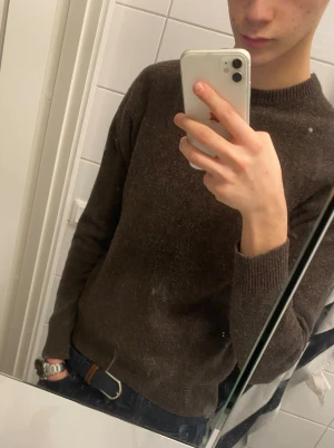 Mörkbrun stickad tröja från Sand West - Snygg mörkbrun stickad tröja från Sand West med rund hals och ribbade muddar. Perfekt för dig som gillar enkel och stilren design. Långärmad modell som passar till jeans eller chinos. Materialet är mjukt och håller dig varm under kyliga dagar.