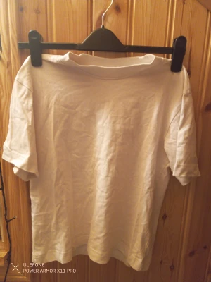 Vit t-shirt från Gina Tricot XS - En klassisk vit t-shirt från Gina Tricot, Basicly Basics-kollektionen. Modellen har rund hals och korta ärmar, perfekt för en clean och enkel look. Materialet är mjuk bomull som känns skönt mot huden. Passformen är normal och funkar till allt.