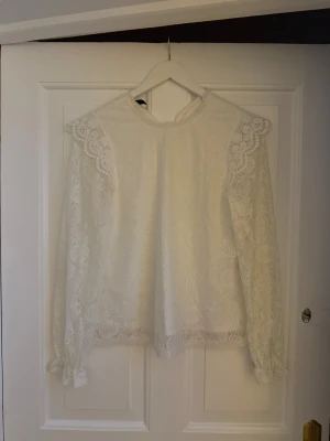 Vit spetsblus från Pieces XS - Supersöt vit blus från Pieces i storlek XS, helt i spets med långärmade ärmar och fina volangdetaljer vid axlar och ärmslut. Aldrig använd ❤️