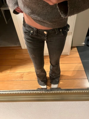 True Religion Joey Bootcut Jeans grå - Säljer ett par svarta True Religion Joey jeans med låg midja och bootcut. Klassiska fickor med lock och silverfärgade knappar bak, samt tydliga sömmar. Jeansen är i stretchigt denim och har en snygg faded look. Kolla noga på dem sista 2 bilderna!!!!!!!!!