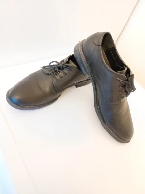 Svarta klassiska finskor med snörning - Snygga svarta skor med rund tå och snörning. Perfekt för dig som gillar stilrena och tidlösa skor. Platt sula och enkel design gör dem lätta att matcha med olika outfits. Bekväma.