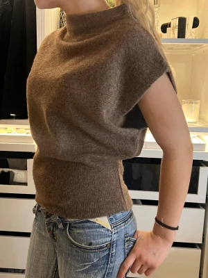 Brun stickad - Säljer en brun stickad polotopp med korta ärmar och hög hals. Tröjan är från Nelly i ett nu skick
