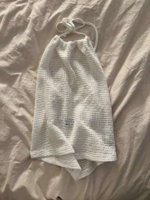 Vit stickad halterneckklänning Gina Tricot - Supersöt vit stickad kortklänning från Gina Tricot i halterneck-modell med knyt i nacken. Klänningen är ärmlös och har ett luftigt, virkat mönster, knappt andvänd!