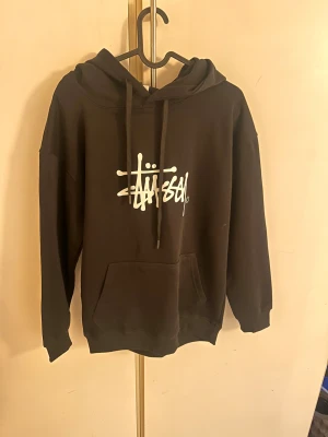  Stüssy hoodie  - Svart hoodie från Stüssy med vit logotyp på bröstet och tryck på huvan. Ny pris ligger på ca 1400kr men säljer endast för 349