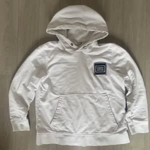Burberry London England - S - Snygg vit hoodie från Burberry London England med klassisk logopatch på bröstet. Tröjan har huva, magficka och ribbade muddar vid ärmslut och nederkant. Perfekt för dig som gillar stilrena och exklusiva plagg med streetkänsla. Storlek S!