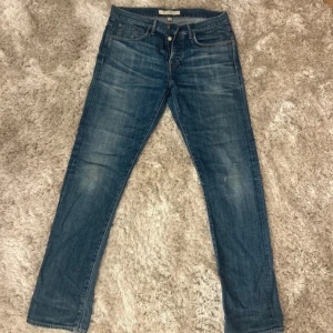 Blå jeans från Burberry W 32 L 32 - Snygga blå jeans från Burberry  raka ben. Jeansen har en mörk tvätt med detaljer i mässing. Tillverkade i jeansmaterial och passar dig som gillar stilren, grisch och tidlös look. Storlek W 32 L 32. Tveka inte på att höra av dig vid minsta fundering.