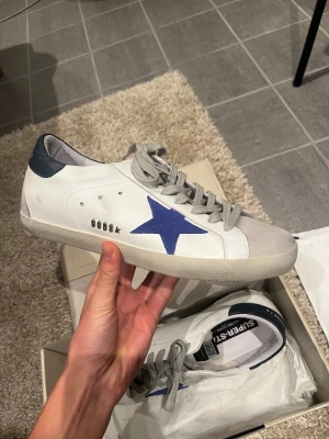 Golden Goose Super-Star sneakers vit/blå - Hej! Säljer nu dessa väldigt fräscha skor från golden goose || Det är i princip helt nya || box, dustbag, äkthets kuvert och orderbekräftelse tillkommer || Hör av dig vid frågor eller funderingar!!🌟👏FRAKTAR SAMMA DAG!