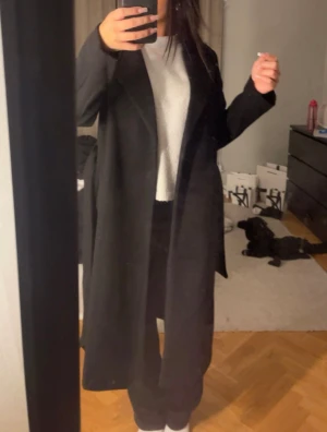 Svart lång kappa  - Säljer en svart lång kappa med rak passform och klassisk krage. Perfekt för dig som gillar stilrena och tidlösa plagg. Jackan har långa ärmar och en enkel, elegant design som passar till det mesta.