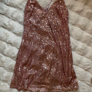 Glittrig rosa kortklänning Victoria's Secret - Supersnygg rosa kortklänning från Victoria's Secret med glittriga paljetter över hela klänningen. Klänningen har v-ringad hals, tunna axelband och ett mjukt meshfoder på insidan. Perfekt för dig som vill sticka ut med extra glam och shimmer.