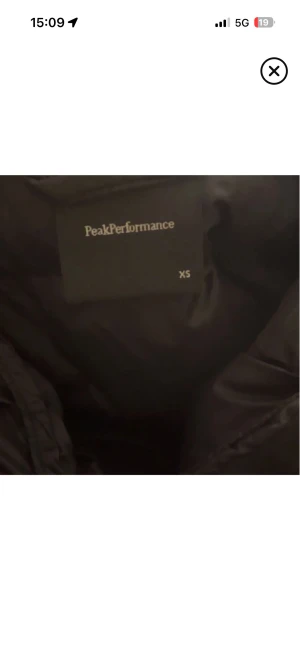 Svart dunjacka Peak Performance XS - Svart dunjacka från Peak Performance i storlek XS. Jackan har huva, quiltad design och dragkedja framtill. Perfekt för kalla dagar och har en stilren look med logga på bröstet. Långärmad och med puffad form för extra värme.