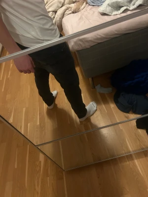 Svarta jeans från Nudie Jeans - Säljer ett par svarta skinny jeans från Nudie Jeans med klassisk femficksdesign och snygg broderad detalj på bakfickan. Jeansen har låg midja och sitter tight hela vägen ner, perfekt för dig som gillar en smal siluett. Materialet är mjukt och stretchigt denim. 