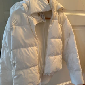 ALO puffer jacket Ivory - Säljer en snygg vit pufferjacka från ALO köpt i LA med huva och dragkedja. Jackan är quiltad och har en modern, lite kortare passform. 