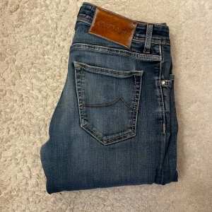 Jacob Cohen Jeans - Snygga blå jeans från Jacob Cohen, modell Nick, med exklusiv brun patch i päls och detaljerade sömmar i rött. Passar dig som är 180-185 cm,Tillverkade i Italien med lyxig känsla och klassisk femficksdesign. Passar dig som gillar premium denim och stilrena detaljer.  Hör av dig om du har frågor😀👊