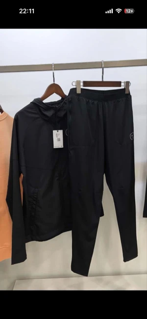 Svart Nike Air vindjacka med huva - Svart vindjacka från Nike Air med huva och dragkedja framtill. Jackan har en stilren design med Nike-logga och AIR-tryck på ryggen. Tillverkad i lätt polyester som passar perfekt för träning eller chill. Snygg och funktionell för dig som gillar sportig stil.