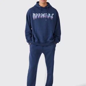 Blå tracksuit från boohooman - Den är helt oanvänd och jag råkade beställa fel storlek på den och försöker sälja den. Det är en  snygg marinblå hoodie från boohooman med stort, vågigt tryck i blått och lila på bröstet. Tröjan har huva med dragsko och en stor magficka. Perfekt för dig som gillar streetwear.