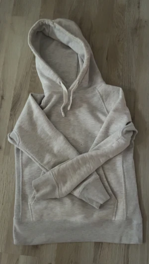 Ljusgrå hoodie från Russemerch - Ljusgrå hoodie från R med klassisk huva och snörning. Mjuk insida och ribbade muddar vid ärmslut och nederkant. Perfekt för chill dagar och enkel att matcha med jeans eller joggers. Snygg och enkel design utan tryck.