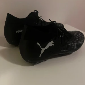 PUMA FUTURE 8 MATCH FG/AG ECLIPSE - PUMA SVART/GRÅ/GRÖN - Hej! Jag säljer ett par PUMA FUTURE 8 MATCH FG/AG ECLIPSE i färgen svart/grå/grön.  Jag säljer dem eftersom jag slutade spela fotboll i somras och därför knappt har använt dem sedan dess. Skorna är bara några månader gamla och i mycket fint skick. De har inte använts på hårt underlag och är välvårdade. De är fräscha och luktar nästan som nya.  Nypris: 879 kr på Unisport. Mitt pris: 599 kr | ett rimligt och rättvist pris.  Ta även gärna en titt på ett par Adidas inomhusskor jag säljer!