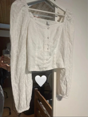 Vit broderad blus med puffärm - Vit blus med knappar framtill och dragkedja vid sidan. Knappt använd, som ny!