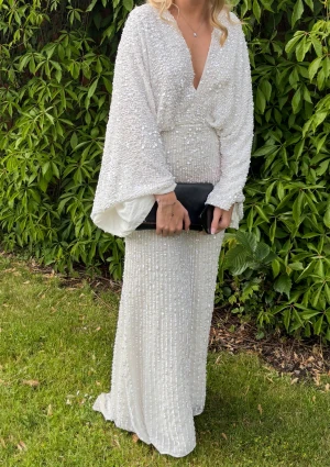 Vit glittrig balkläning Asos - Säljer min fina balkläning från Asos. Förra ägaren har sytt upp den lite men jag är ungefär 170 cm och passade mig bra då jag inte hade någon klack. Förra ägaren sydde även igen urringningen lite. Efter min användning är den tvättad men kan sakna någon paljett men inget man tänker på. Klänningen är otroligt fin och unik då den inte säljs längre 