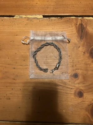 Cordell armband - Snyggt armband i silverfärgad metall med flätad kedja och karbinlås. Kommer med en liten genomskinlig tygpåse för förvaring. Perfekt accessoar för dig som gillar stilrena detaljer och vill ha något som sticker ut lite extra. (Säljer för att passar inte mig)