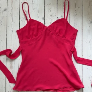 Fin topp från Reserved 💕 - Snygg rosa topp från Reserved med smala axelband och omlottknytning i midjan. Klänningen har en v-ringad byst och figurnära passform som framhäver siluetten. Storlek M 💞💞 Köpt för 400kr från Vinted. Aldrig använd, för stor för mig! Skriv om ni har några frågor! 