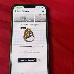 Guldig statementring med stenar - Unik guldig ring med ett öppet, rutnätsliknande mönster och små gnistrande stenar infällda i designen. Ringen har en avlång, spetsig form som täcker en stor del av fingret och ger en riktigt cool och iögonfallande look.