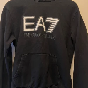 Svart hoodie från Emporio Armani EA7 - Svart hoodie från Emporio Armani EA7, tröjan är i storlek s. 