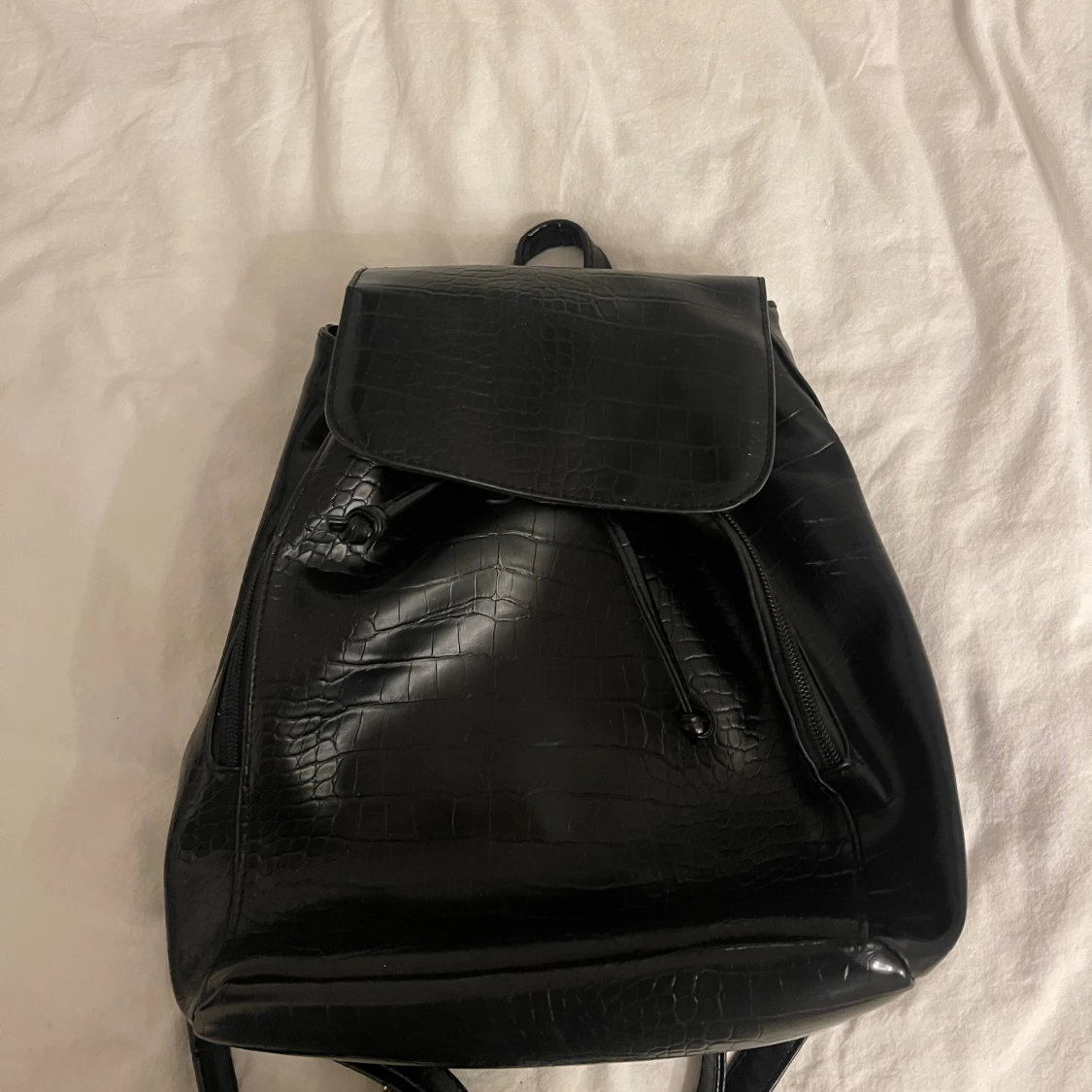 Svart ryggsäck med krokopräglad yta