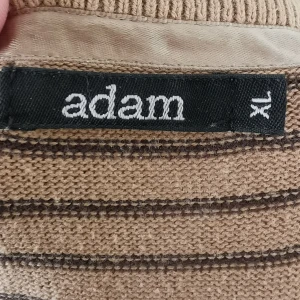 Beige och brun randig tröja Adam XL - Säljer en beige och brun randig tröja från Adam i storlek XL. Tröjan är tillverkad i 100% bomull och har långa ärmar med breda muddar. Perfekt för dig som gillar klassiska ränder och vill ha en skön och stilren look.