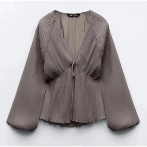 Grå blus från Zara - Säljer en snygg grå blus från Zara med långa, vida ärmar. Blusen har v-ringning och knyt framtill. 💞