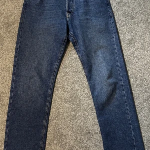 Blå jeans från Jack & Jones, 30/32 - Klassiska blå jeans från Jack & Jones med raka ben och normal passform. Jeansen har fem fickor, snygga kontrastsömmar och en läderpatch bak i midjan. Tillverkade i slitstarkt bomullsjeansmaterial, perfekta för en avslappnad stil.